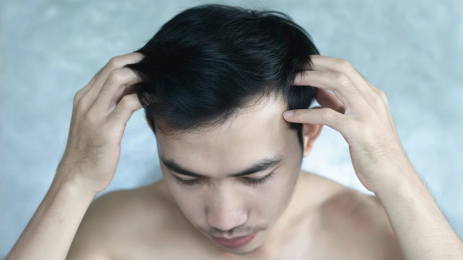 一位光膀子男性正在近距离检查自己的发际